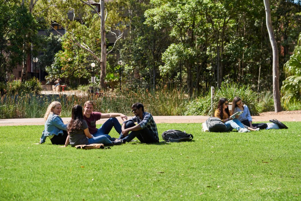 Students socialising on grass outside University of Wollongong during lecture break