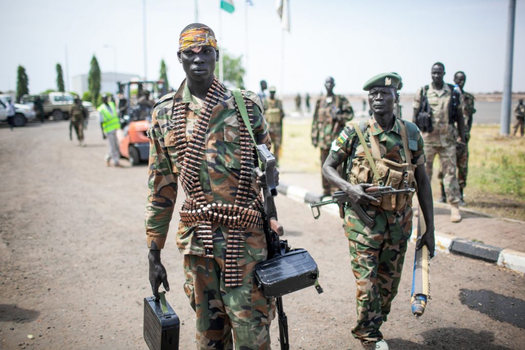 A heavily armed Sudanese soldier carrying a machine gun and ammunition