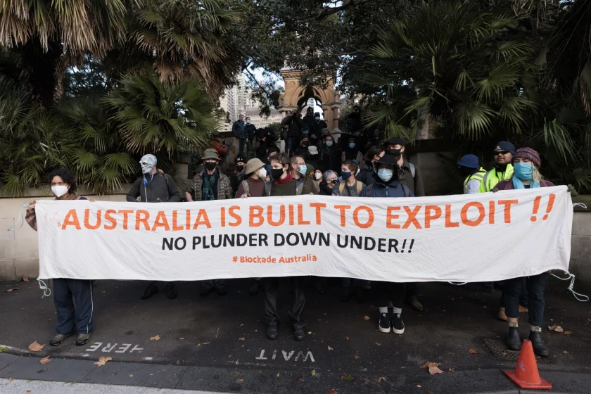 Blockade Australia protesters in Sydney on 27 June 2022 holding a large banner with the message Australia Is Built To Exploit!! No Plunder Down Under!!
